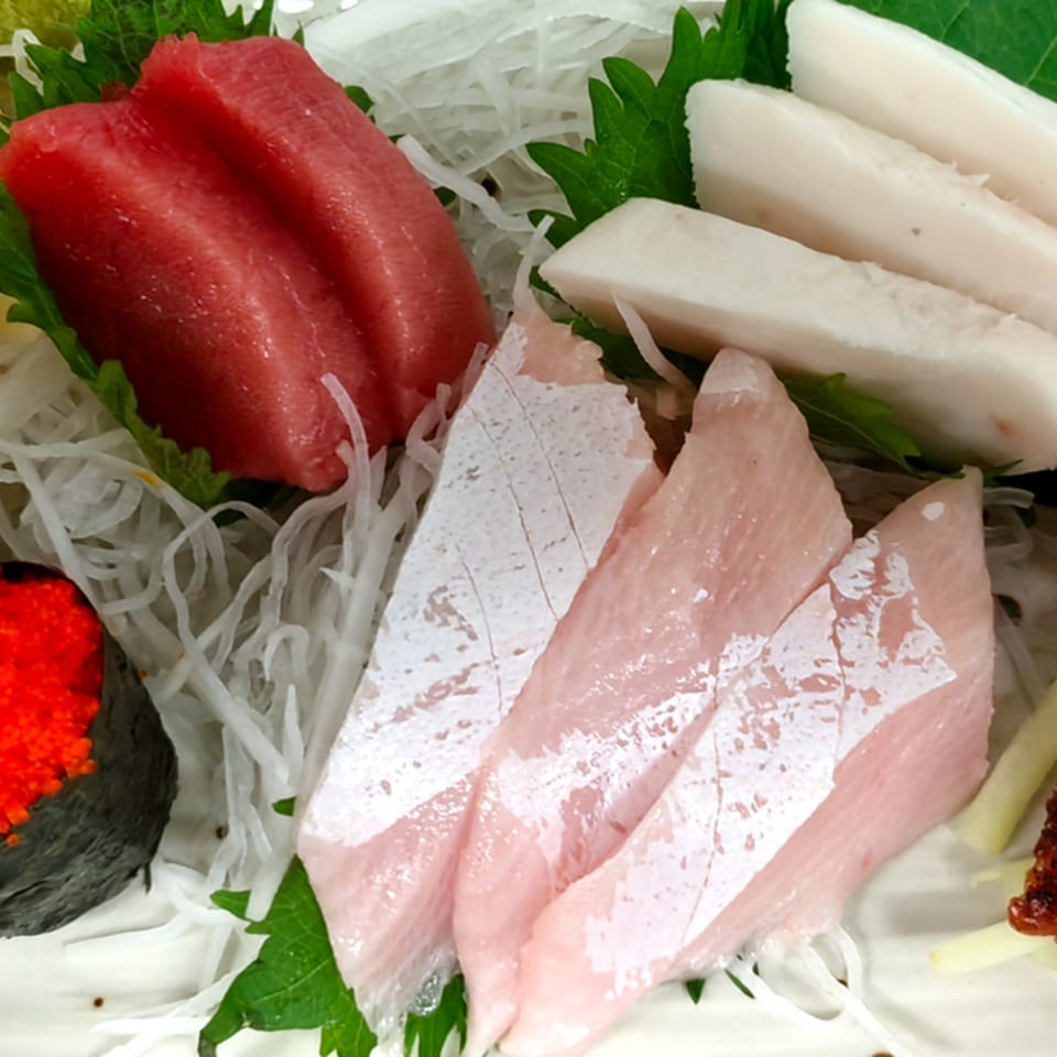 Assortment of fresh Ito Sushi sashimi, including red tuna, white fish, and light pink fish.